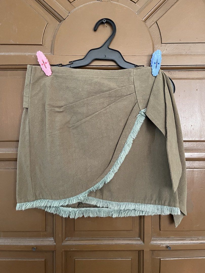 Olive Green Fringed Wrap Mini Skirt (Category: Skirts) located in Manila. Submitted by ellesmr122 (Listing ID 1460323220, Image 1). Description: - Olive green mini skirt - Wrap style with side tie detail - Frayed fringe hem - Estimated size S or M - Ideal for casual outings.