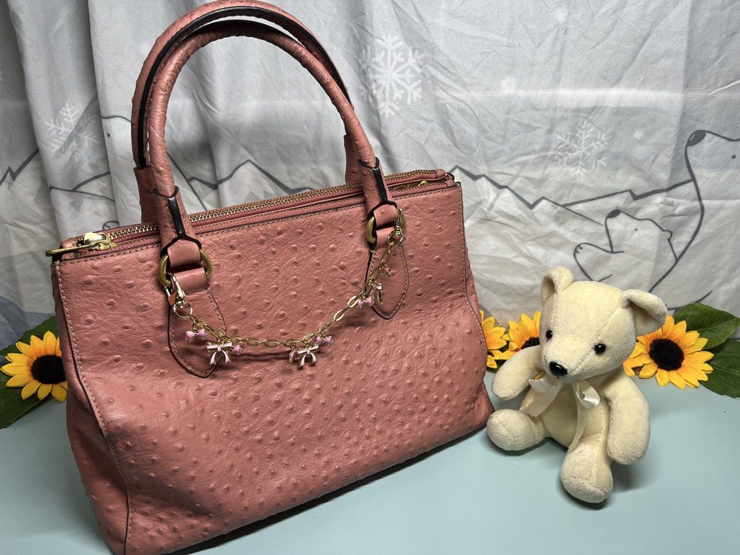 Pink Ostrich Embossed Handbag with Bow Charm (Category: Luxury Bags & Wallets) located in Liloan. Submitted by sakurumifinds2809 (Listing ID 1460355692, Image 2). Description: - Adorable pink handbag with a unique ostrich-like texture. - Elegant gold hardware. - Secure top zip closure. - Spacious interior with multiple compartments for organization. - Handles show some signs of wear. - Versatile for everyday errands or a stylish night out. -Can f
