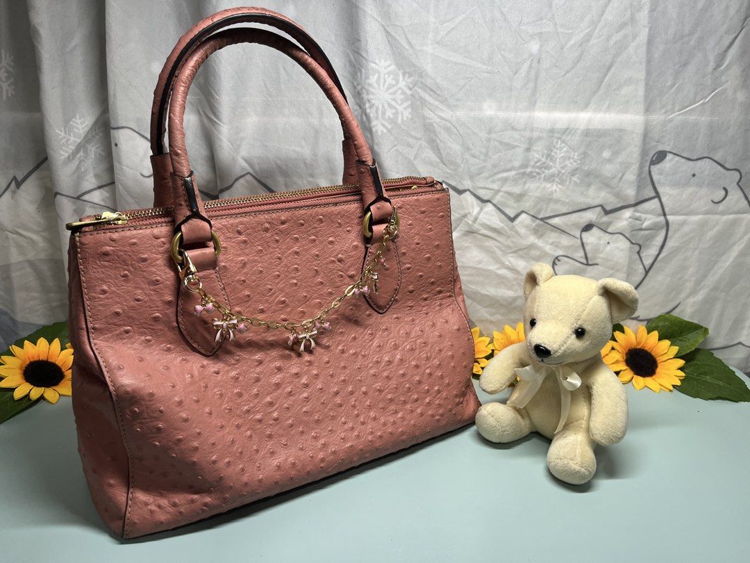 Pink Ostrich Embossed Handbag with Bow Charm (Category: Luxury Bags & Wallets) located in Liloan. Submitted by sakurumifinds2809 (Listing ID 1460355692, Image 1). Description: - Adorable pink handbag with a unique ostrich-like texture. - Elegant gold hardware. - Secure top zip closure. - Spacious interior with multiple compartments for organization. - Handles show some signs of wear. - Versatile for everyday errands or a stylish night out. -Can f