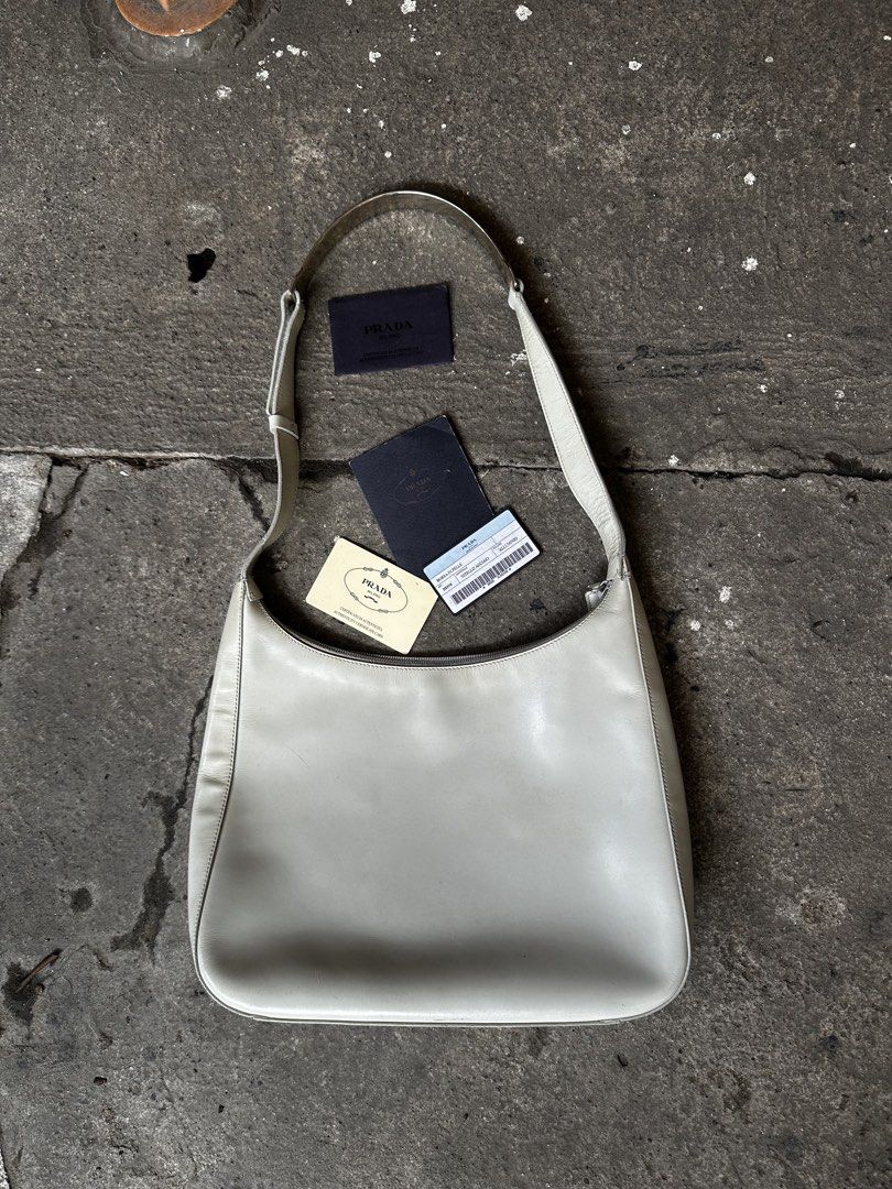 Prada cleo shoulder bag (Category: Luxury Bags & Wallets) located in Quezon City. Submitted by la.deals (Listing ID 1460365417, Image 2). Description: - Authentic Prada shoulder bag - Color: Light grey leather - Includes authenticity cards - Unique buckle detail on strap - Ideal for everyday use.
