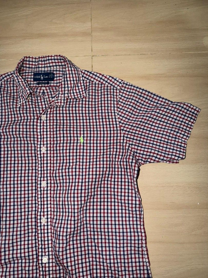 Ralph Lauren Gingham Short Sleeve Shirt (Category: Tshirts & Polo Shirts ) located in Cainta. Submitted by hermosooo (Listing ID 1460432101, Image 2). Description: - Classic Ralph Lauren short sleeve shirt - Red, white, and blue gingham pattern - Iconic embroidered polo player logo on chest - Button-down style - Perfect for casual wear.