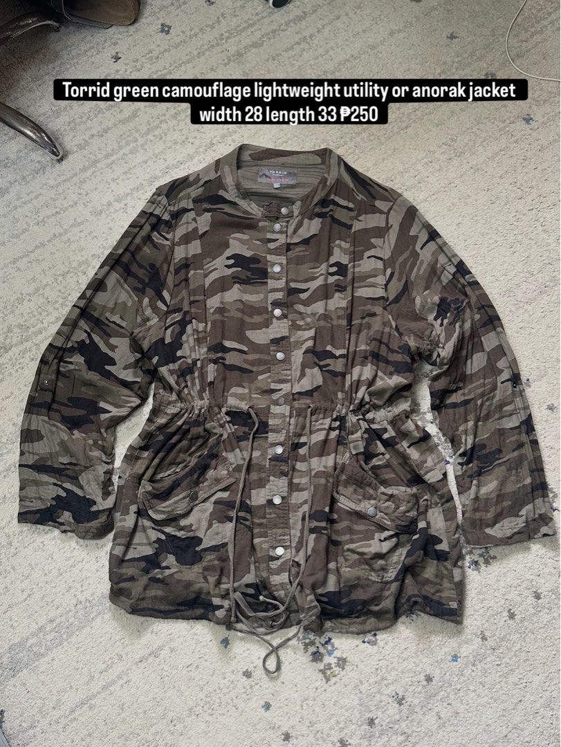 Torrid Green Camouflage Lightweight Utility Anorak Jacket (Category: Coats, Jackets and Outerwear) located in Daet. Submitted by thrifthings2018 (Listing ID 1460343892, Image 1). Description: - Torrid green camouflage utility/anorak jacket - Lightweight material - Adjustable drawstring waist - Button front closure - Two front pockets - Measurements: Width 28 inches, Length 33 inches - Ideal for casual wear.