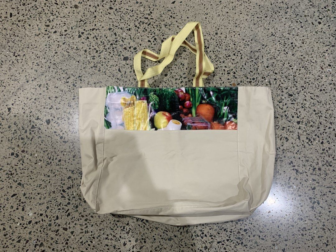 Tote Bag with Fruit and Vegetable Print (Category: Tote Bags) located in Las Pinas. Submitted by p.j.c.a.r.o.u.s.e.l.l.i.n.g (Listing ID 1460325703, Image 1). Description: - Water resistant grocery bag Stylish beige tote bag - Vibrant fruit and vegetable print on front pocket - Yellow straps with brown stripes - Ideal for grocery shopping or everyday use - Spacious interior for all your essentials - Comfortable and easy to carry.
