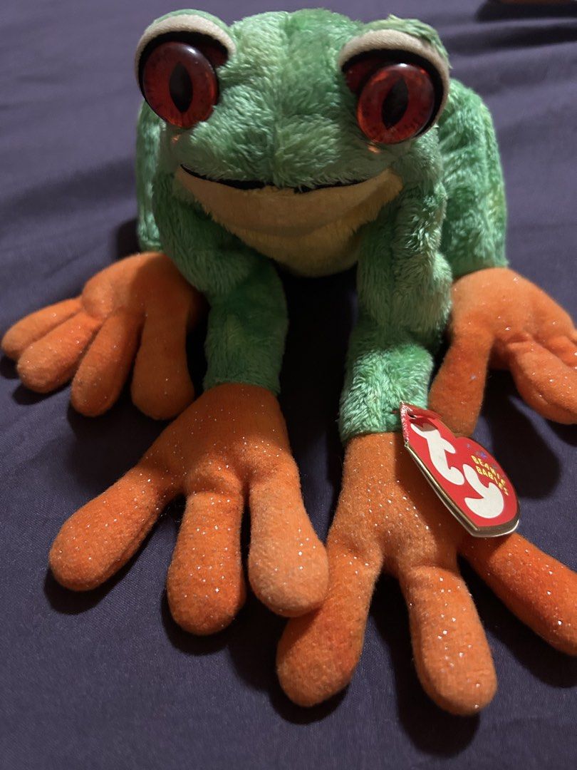 Ty Beanie Babies "Ribbit" Frog Plush Toy (Category: Plushies & Soft Toys) located in Pasig City. Submitted by mixpicks (Listing ID 1460306409, Image 2). Description: - Adorable green frog plush toy - Features big red eyes - Sparkly orange feet add a unique touch - Original Ty tag still attached - Ideal for Ty collectors or as a charming gift - A fun and friendly companion - Vintage stuff ( owned for a long time).