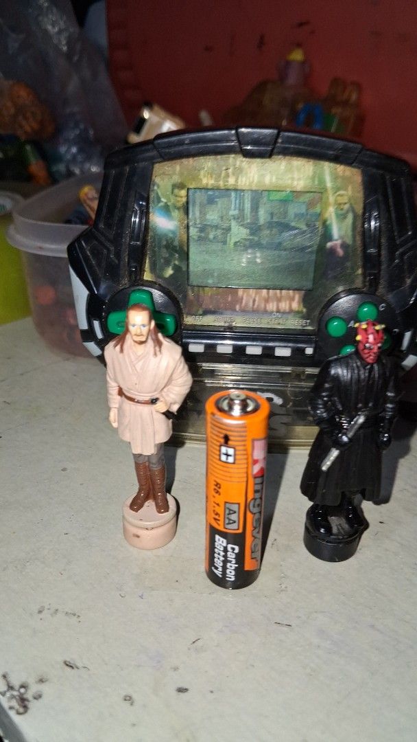 Vintage Star Wars Electronic Handheld Game with Figures (Category: Action & Battle Toys) located in Manila. Submitted by marcas022798212 (Listing ID 1460450944, Image 1). Description: - Vintage Star Wars electronic handheld game - Includes Darth Vader and Obi-Wan Kenobi figures - Features a game scene on the screen - Battery compartment visible - Kingever AA battery included for size reference - Ideal for Star Wars collectors and retro gaming ent