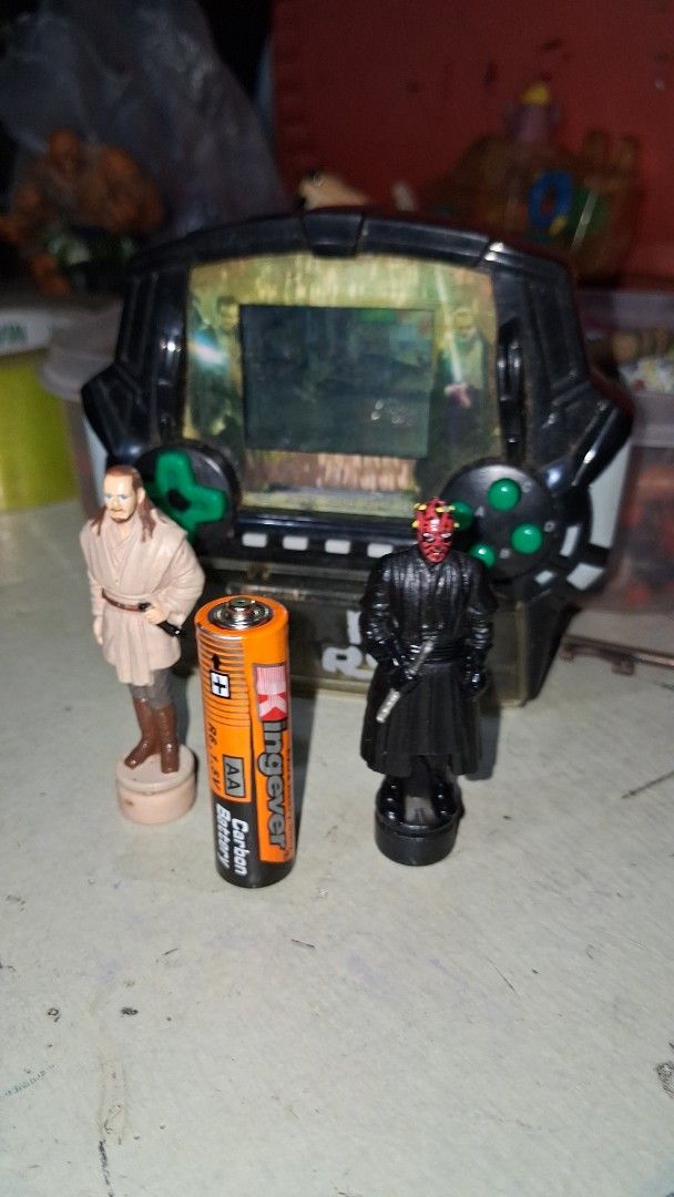 Vintage Star Wars Electronic Handheld Game with Figures (Category: Action & Battle Toys) located in Manila. Submitted by marcas022798212 (Listing ID 1460450944, Image 2). Description: - Vintage Star Wars electronic handheld game - Includes Darth Vader and Obi-Wan Kenobi figures - Features a game scene on the screen - Battery compartment visible - Kingever AA battery included for size reference - Ideal for Star Wars collectors and retro gaming ent