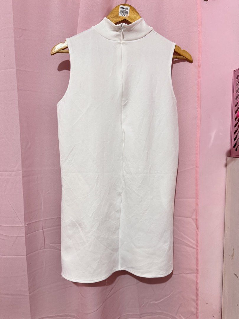 White Mock Neck Sleeveless Top (Category: Sleeveless) located in Valenzuela. Submitted by declutterlangpo (Listing ID 1460495175, Image 3). Description: - White sleeveless top - Mock neck design - Small black logo on left side - Zipper closure at the back - Ideal for layering or wearing alone - Versatile addition to your wardrobe.