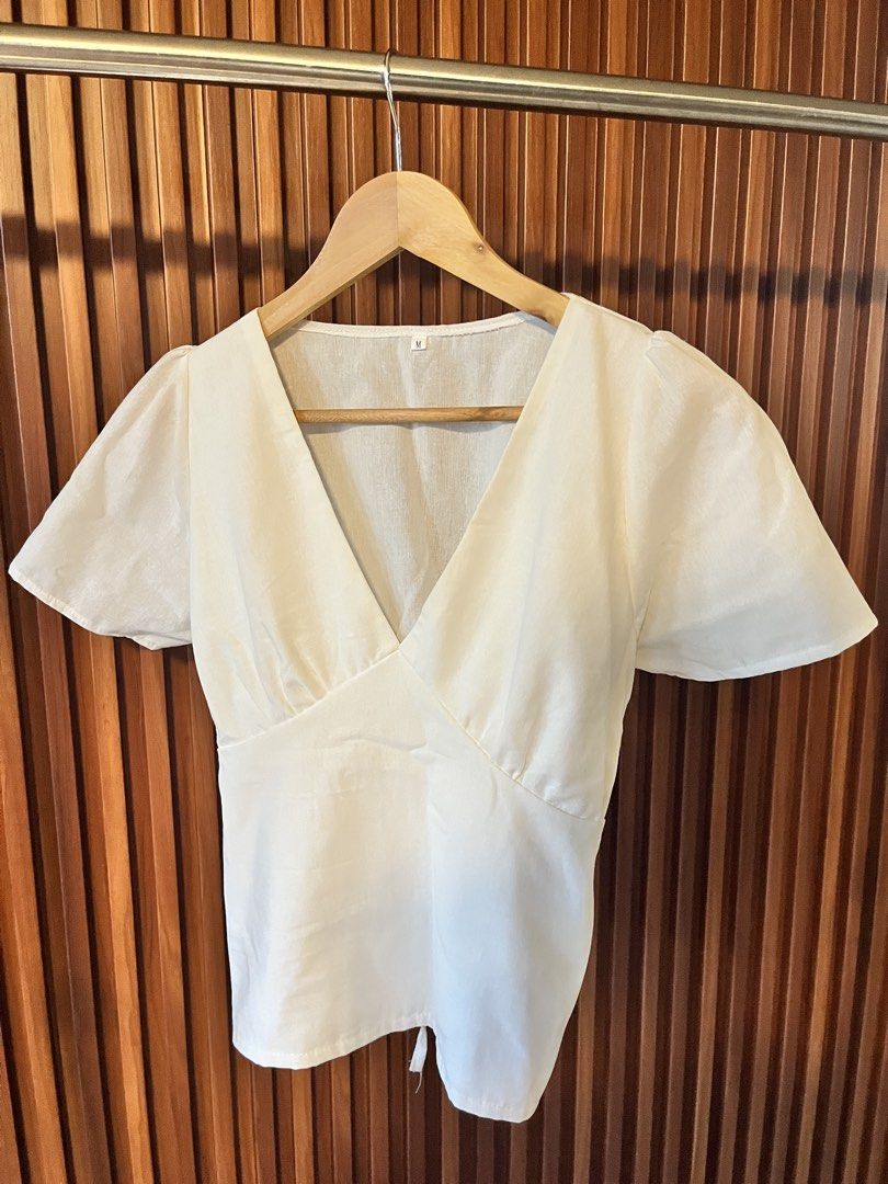 White V-neck Puff Sleeve Top Size M (Category: Blouses) located in Echague. Submitted by aeafitz (Listing ID 1460364660, Image 1). Description: - Elegant white V-neck top - Stylish puff sleeves - Flattering wrap-style front - Slightly cinched waist for a defined silhouette - Unique tie detail at the bottom hem - Made from a comfortable linen or linen-blend fabric - Versatile for casual outings or dressing up.