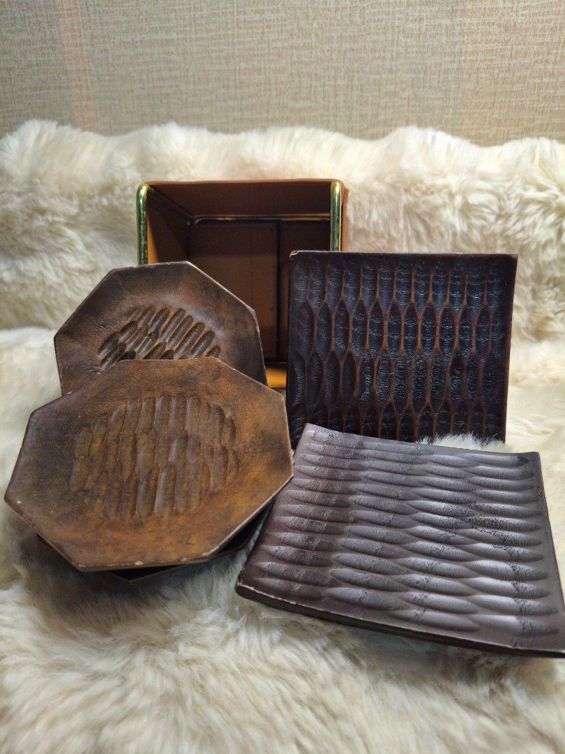 Wood carved coasters bundle (Category: Other Kitchenware & Tableware) located in Rizal. Submitted by emskititay (Listing ID 1460446676, Image 2). Description: - Set includes 4 dark brown hexagonal and 2 square coasters with carved patterns. - Comes with a stylish tan leather holder with gold accents. - Holder keeps coasters neatly stored. - Adds a touch of elegance to your coffee table or home bar..