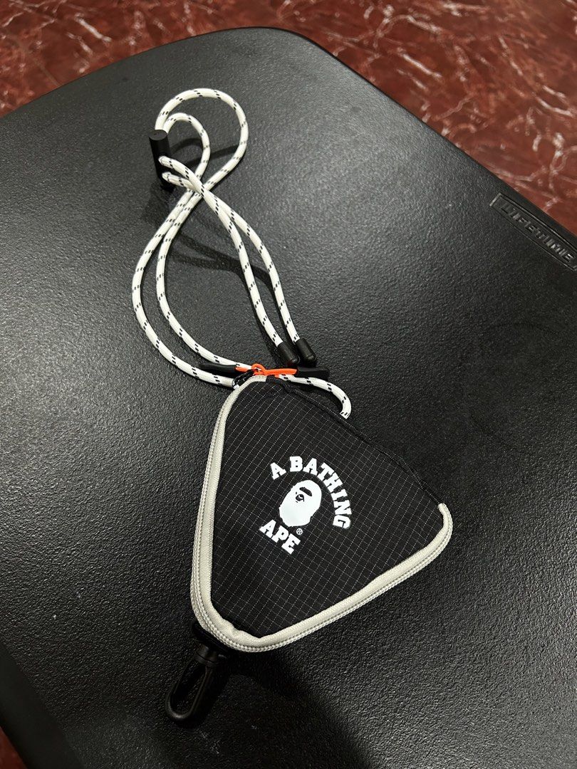 A Bathing Ape BAPE Pouch with Lanyard (Category: Purses & Pouches) located in Manila. Submitted by drilskie0954204 (Listing ID 1460516008, Image 1). Description: - Authentic A Bathing Ape (BAPE) triangular pouch - Features the iconic BAPE logo graphic - Secure zipper closure - Includes small interior pockets for organization - Comes with a white and black rope lanyard - Ideal for carrying small daily essentials.
