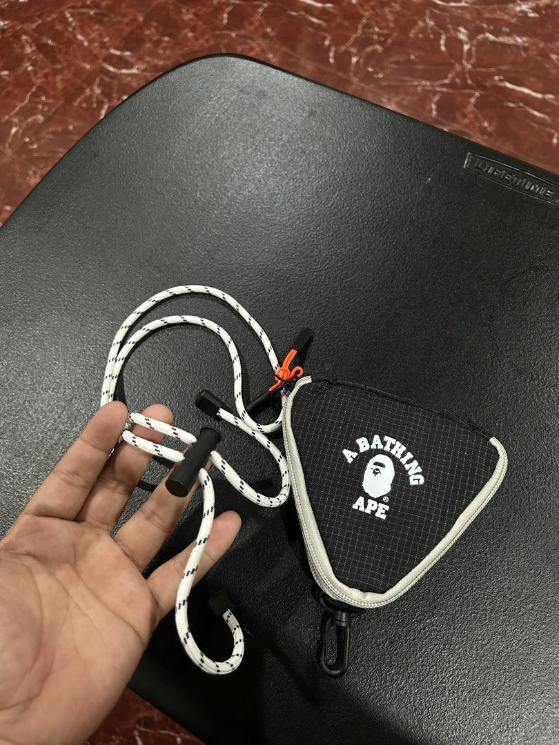 A Bathing Ape BAPE Pouch with Lanyard (Category: Purses & Pouches) located in Manila. Submitted by drilskie0954204 (Listing ID 1460516008, Image 2). Description: - Authentic A Bathing Ape (BAPE) triangular pouch - Features the iconic BAPE logo graphic - Secure zipper closure - Includes small interior pockets for organization - Comes with a white and black rope lanyard - Ideal for carrying small daily essentials.