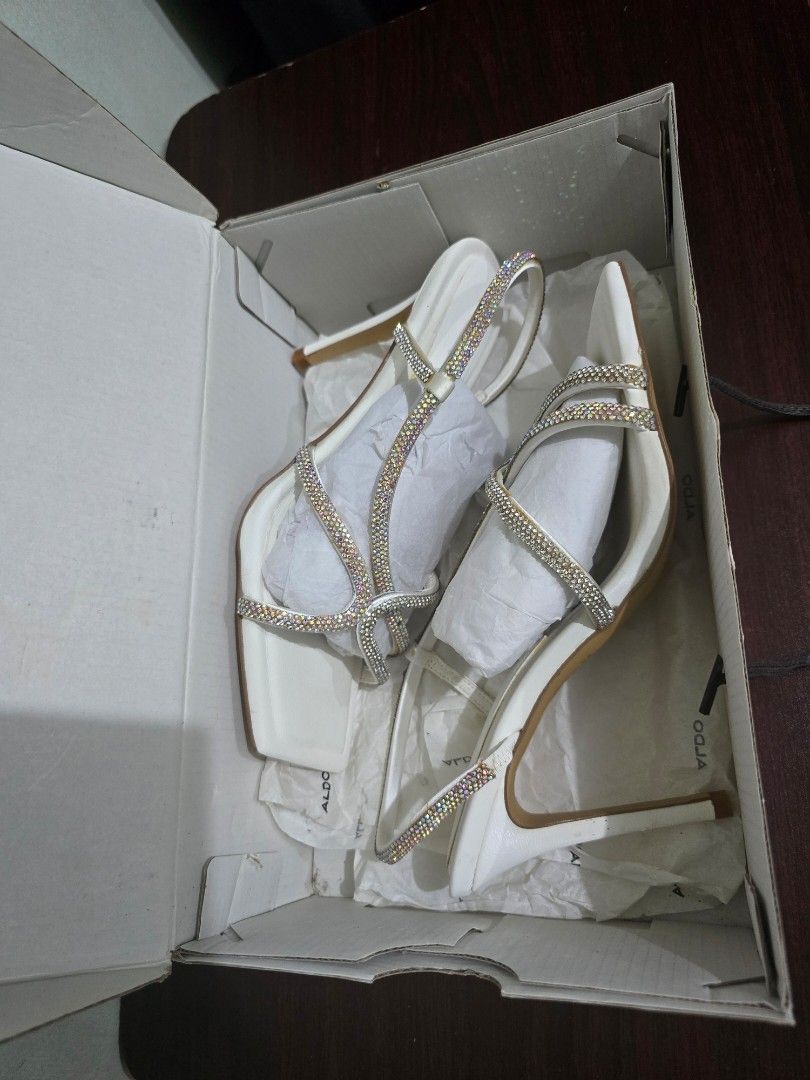 ALDO White Embellished Heeled Sandals (Category: Heels) located in Marikina City. Submitted by bloomsandgreenscollection (Listing ID 1460679596, Image 2). Description: - Brand: ALDO - Size: 5.5 to 6 - Color: White - Style: Heeled Sandals - Features: Rhinestone-decorated straps, Square toe - Condition: Comes with original box - Occasion: Ideal for dressing up outfits.