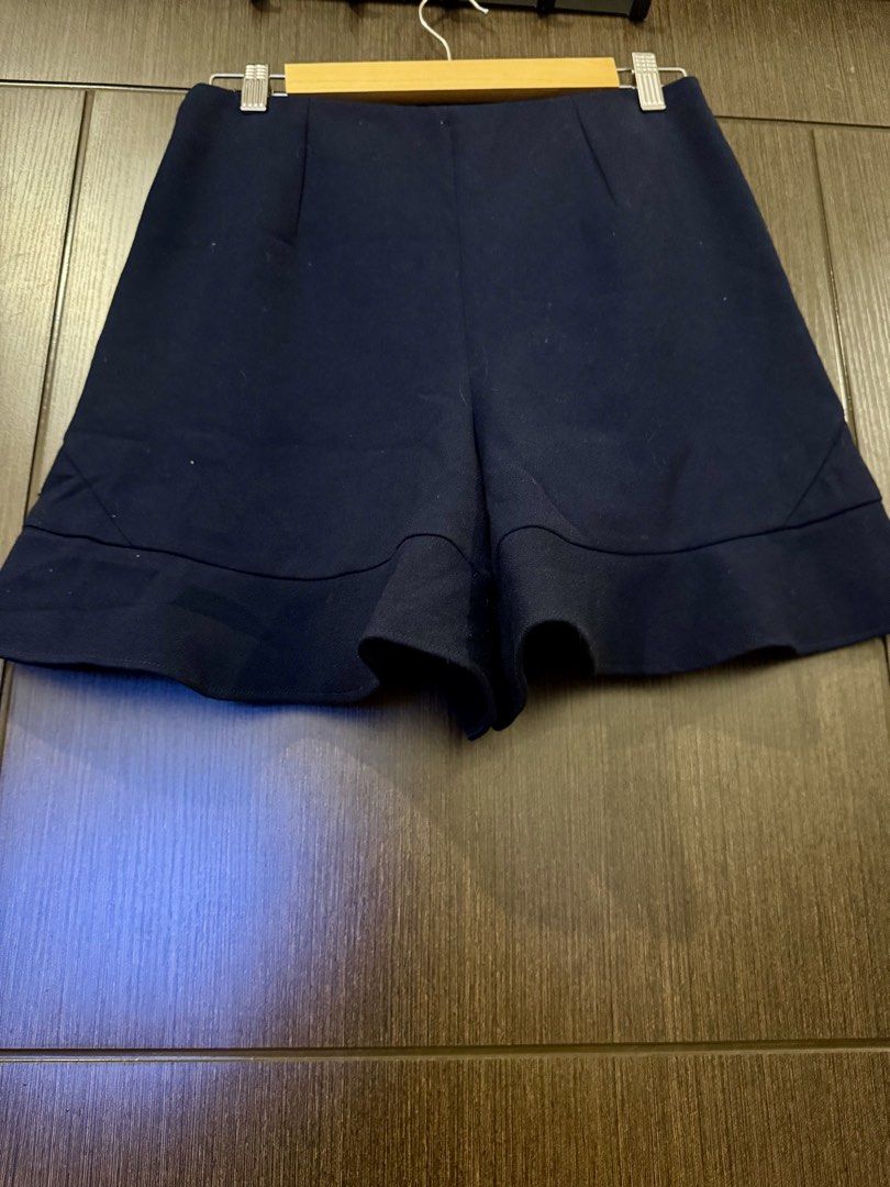Authentic Maje Short (Category: Shorts) located in Quezon City. Submitted by zara_haul (Listing ID 1460685034, Image 3). Description: Design: High-waisted, A-line silhouette featuring a structured top section that flares out slightly into a distinctive flounce or ruffled hemline. Color: Deep navy blue.Features: Subtle darts at the waist for a tailored, form-fitting upper shape, an invisible side zipper closure, and discrete side slip pockets. Sty
