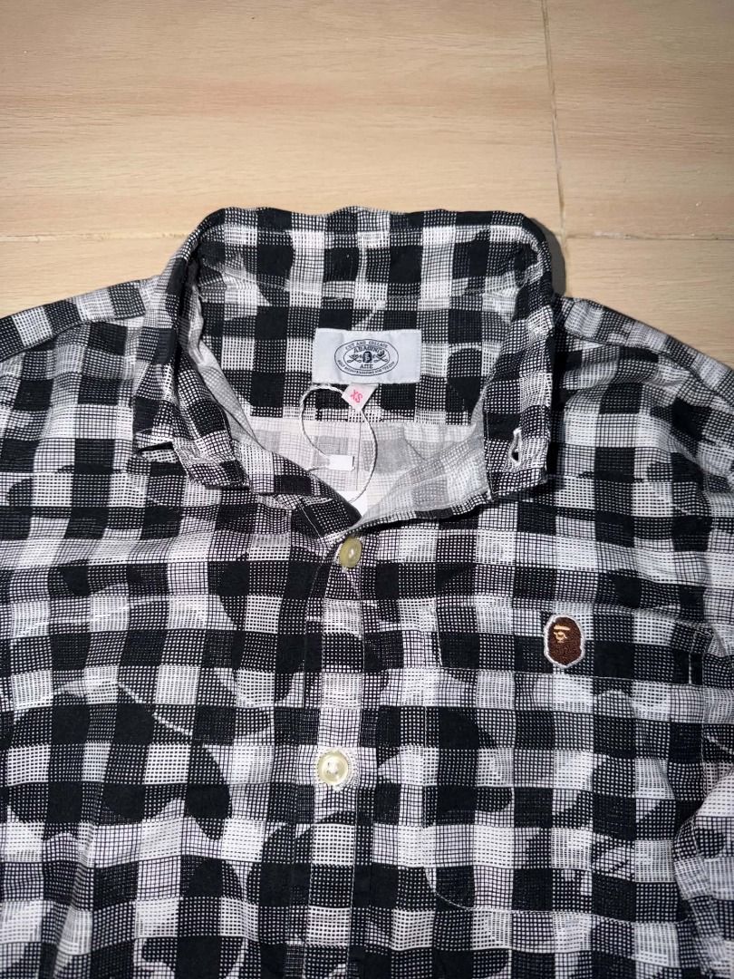 BAPE Black and White Plaid Button-Up Shirt (Category: Tshirts & Polo Shirts ) located in Cainta. Submitted by hermosooo (Listing ID 1460713687, Image 2). Description: - Classic BAPE long-sleeved button-up shirt - Stylish black and white plaid pattern - Features iconic ape head logo on chest pocket - Versatile for pairing with jeans or shorts - Ideal for everyday casual outfits.