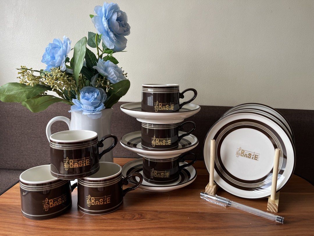 Basie Coffee Cup Saucer Set and Plates (Category: Coffee & Tea Tableware) located in Caloocan City. Submitted by happypenguin-808164 (Listing ID 1460526689, Image 2). Description: - Set includes 4 brown and white coffee cups. - Comes with 4 matching saucers. - Also includes a stack of 5 plates. - All pieces feature a charming gold musical note and 'Basie' logo. - Ideal for enjoying your favorite coffee or tea. - Adds a touch of classic elegance t