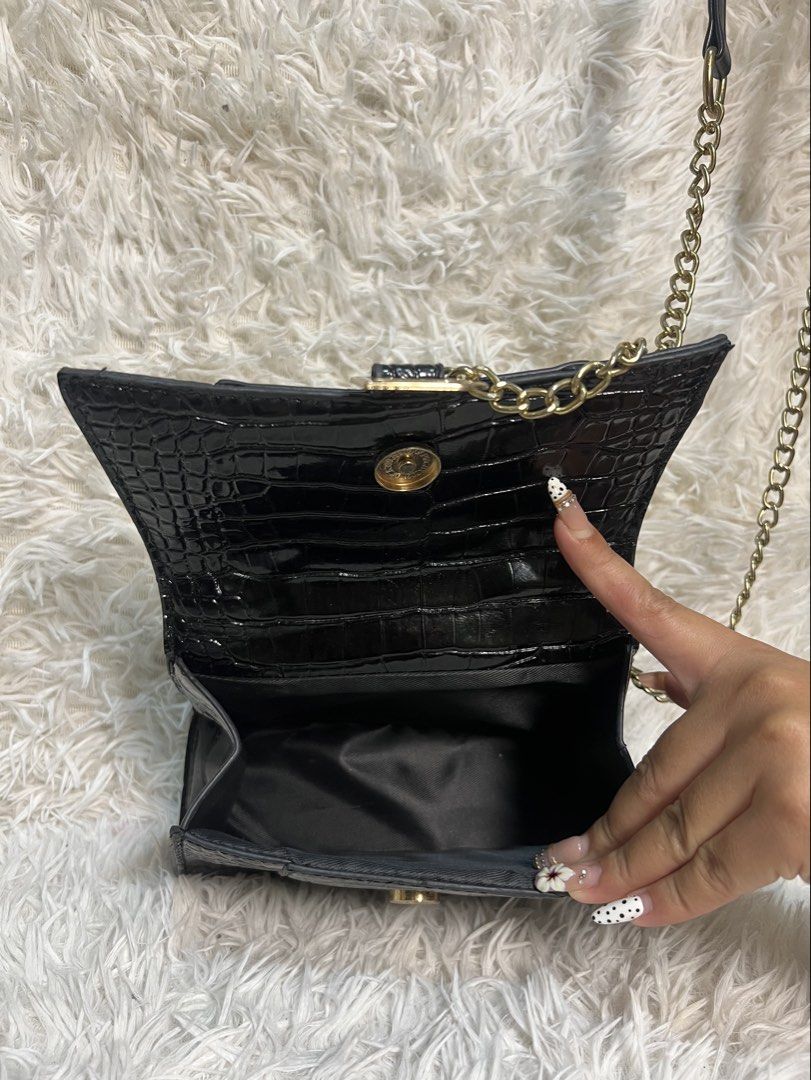 Black Crocodile Embossed Handbag with Gold 'B' Logo (Category: Luxury Bags & Wallets) located in Manila. Submitted by yanya97 (Listing ID 1460541613, Image 3). Description: - Black handbag with luxurious crocodile embossed texture. - Features a stylish gold-tone 'B' logo on the front. - Comes with a comfortable top handle. - Includes a detachable chain strap for versatile wear. - Interior is lined with smooth satin. - Secure clasp closure to keep