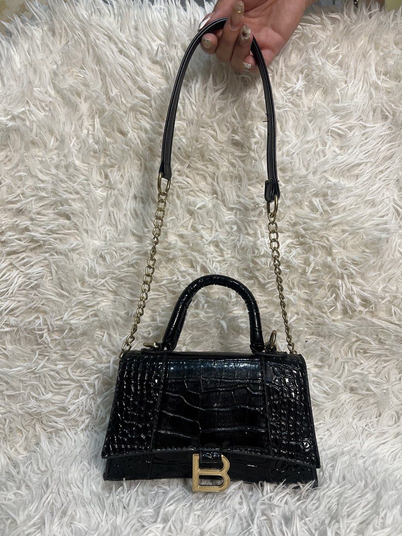 Black Crocodile Embossed Handbag with Gold 'B' Logo (Category: Luxury Bags & Wallets) located in Manila. Submitted by yanya97 (Listing ID 1460541613, Image 2). Description: - Black handbag with luxurious crocodile embossed texture. - Features a stylish gold-tone 'B' logo on the front. - Comes with a comfortable top handle. - Includes a detachable chain strap for versatile wear. - Interior is lined with smooth satin. - Secure clasp closure to keep