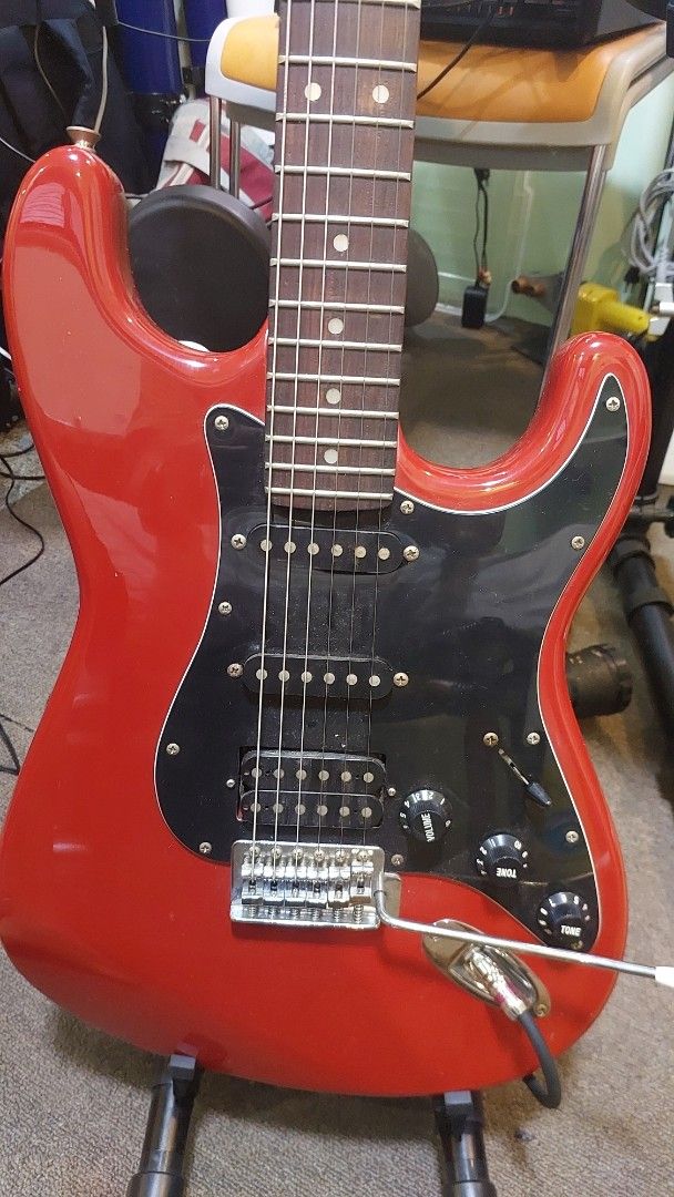 Busker's Red Electric Guitar (Category: Musical Instruments) located in Baliuag. Submitted by papa.gardz (Listing ID 1460673948, Image 1). Description: - Busker's red electric guitar - Stratocaster style - Three pickups - Tremolo bar included - Some wear on back plate near neck - Ideal for playing or as a project guitar.