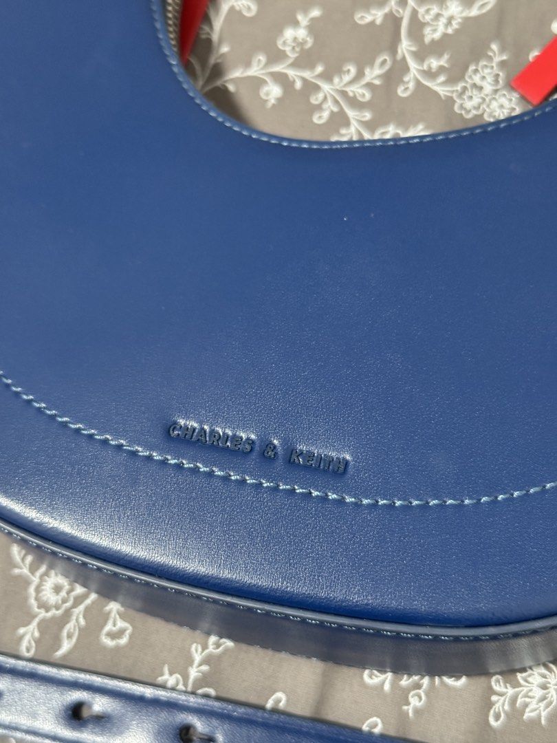 Charles & Keith Blue Crescent Shoulder Bag (Category: Shoulder Bags) located in Quezon City. Submitted by averioph (Listing ID 1460617914, Image 2). Description: - Blue crescent shoulder bag by Charles & Keith - Made of smooth faux leather - Secure zipper closure with red pull tabs - Adjustable shoulder strap - Includes an extra long and short strap - Minimal flaws shown on Photo #3 and #4 .