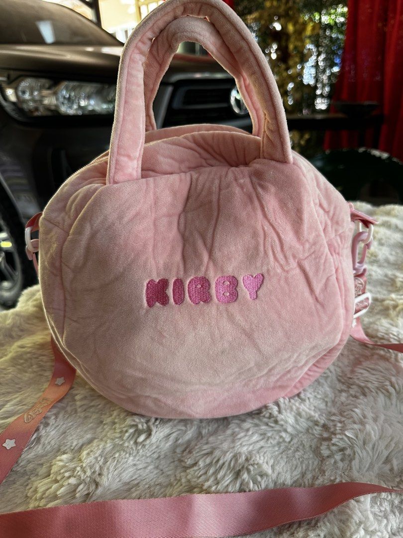 Cute Pink Kirby Plush Round Handbag with Strap (Category: Other Stationery & Craft) located in Digos. Submitted by venusacaro13427 (Listing ID 1460573702, Image 2). Description: - Adorable pink Kirby plush bag - Round and soft design - Features Kirby's iconic face on the front - Includes comfortable handles - Comes with a detachable pink strap printed with 'Kirby' - Ideal for carrying essentials - A must-have for Kirby fans and lovers of cute acc