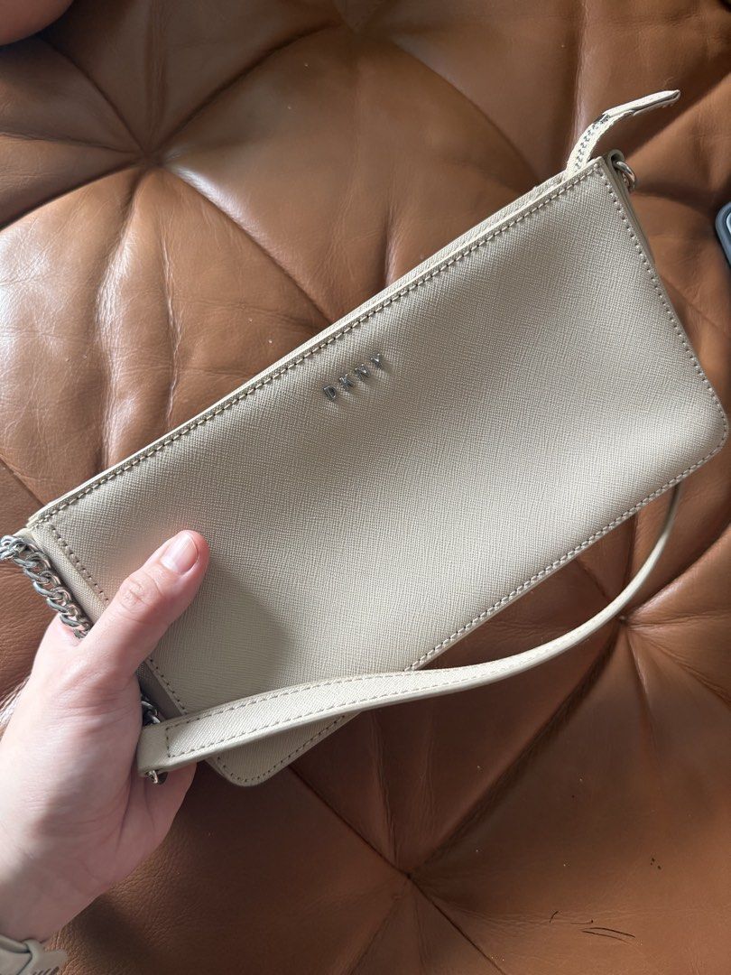 DKNY Beige Shoulder Bag (Category: Shoulder Bags) located in Pasig City. Submitted by angelcstlln (Listing ID 1460520062, Image 2). Description: - Beige DKNY shoulder bag - Textured material - Zipw closure on back pocket - Main compartment zips open - Clean interior lining - Small mark on the front left corner.