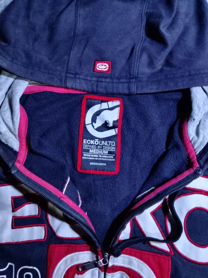 Ecko Unltd. 1972 Zip-Up Hoodie (Category: Coats, Jackets and Outerwear) located in La Trinidad. Submitted by stale_cltv (Listing ID 1460658755, Image 3). Description: - Navy blue Ecko Unltd. zip-up hoodie - Size: Medium - Features iconic Ecko logo and '1972' graphic on the front - Includes a front pocket and hood - Ideal for casual wear.