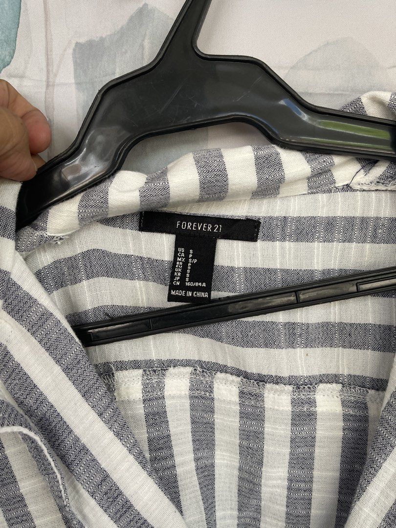 Forever 21 Striped Cropped Button-Up Shirt (Category: Shirts) located in Mandaluyong City. Submitted by coolmeybab (Listing ID 1460539152, Image 2). Description: - Forever 21 grey and white striped long-sleeve shirt - Cropped style with elasticated hem - Button-up front with a collar - Versatile for casual or dressed-up looks - Pairs well with high-waisted jeans or skirts.