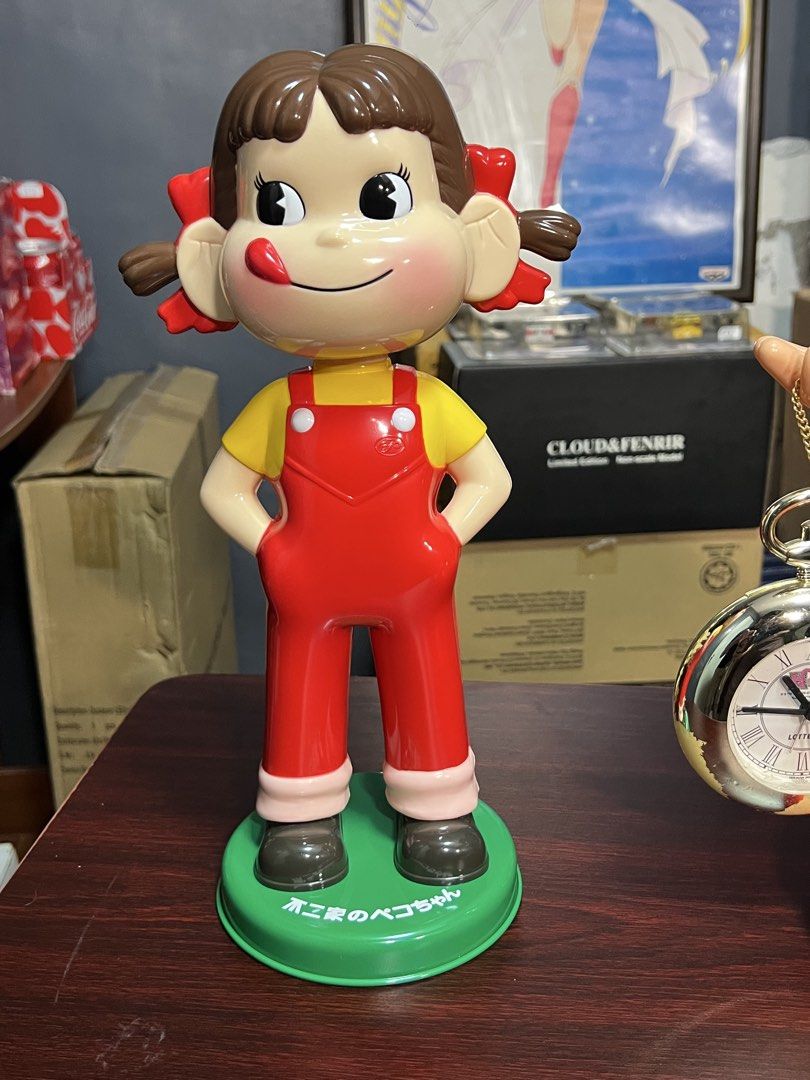 Fujiya Peko-chan Doll Figure (Category: Figurines & Statues) located in Manila. Submitted by thegreyhousemarket (Listing ID 1460700503, Image 1). Description: - Adorable Peko-chan doll from Fujiya - Features iconic red overalls and yellow shirt - Comes with a green display base - Ideal for collectors and fans of Japanese characters - A fun and charming display piece.