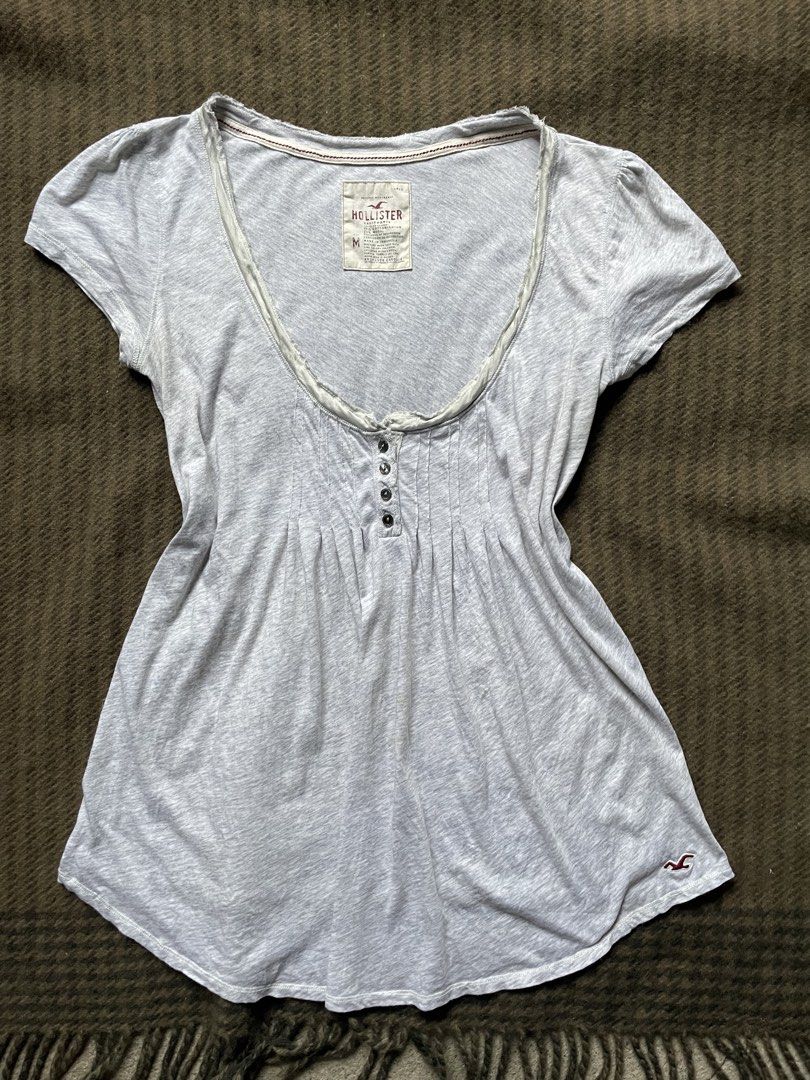 Hollister Grey (Category: Blouses) located in Siniloan. Submitted by rethr1ft (Listing ID 1460674417, Image 1). Description: - Brand: Hollister - Color: Grey - Size: Medium (M) - Neckline: Gathered with button details - Sleeves: Short - Fabric: Soft and stretchy - Condition: Minor faint marks on the front (refer to last photo) - Style: Comfortable casual top.