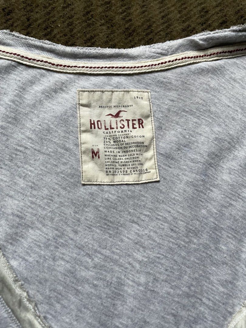 Hollister Grey (Category: Blouses) located in Siniloan. Submitted by rethr1ft (Listing ID 1460674417, Image 2). Description: - Brand: Hollister - Color: Grey - Size: Medium (M) - Neckline: Gathered with button details - Sleeves: Short - Fabric: Soft and stretchy - Condition: Minor faint marks on the front (refer to last photo) - Style: Comfortable casual top.
