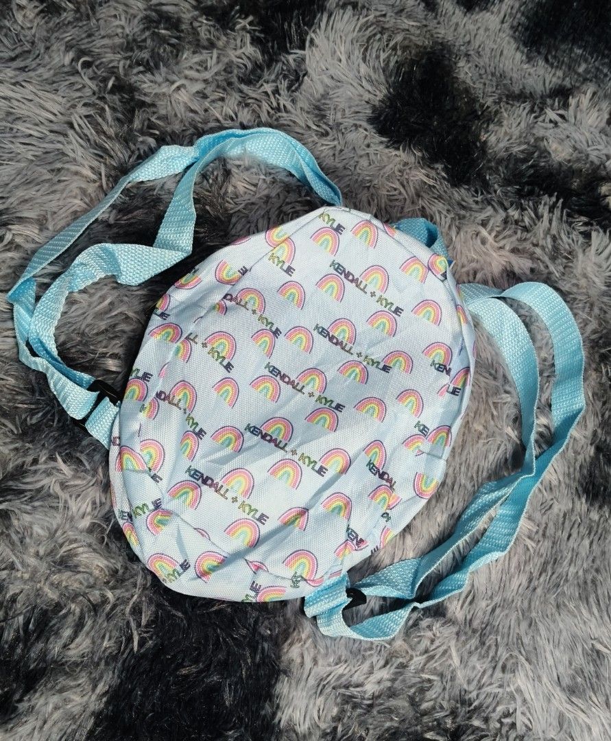 Kendall + Kylie Rainbow Backpack (Category: Backpacks) located in Manila. Submitted by serenitycarlylle (Listing ID 1460704700, Image 1). Description: - Adorable light blue backpack - Features a vibrant rainbow print - "Kendall + Kylie" logo all over - Adjustable blue shoulder straps - Ideal for kids or as a stylish accessory - Compact and lightweight design.