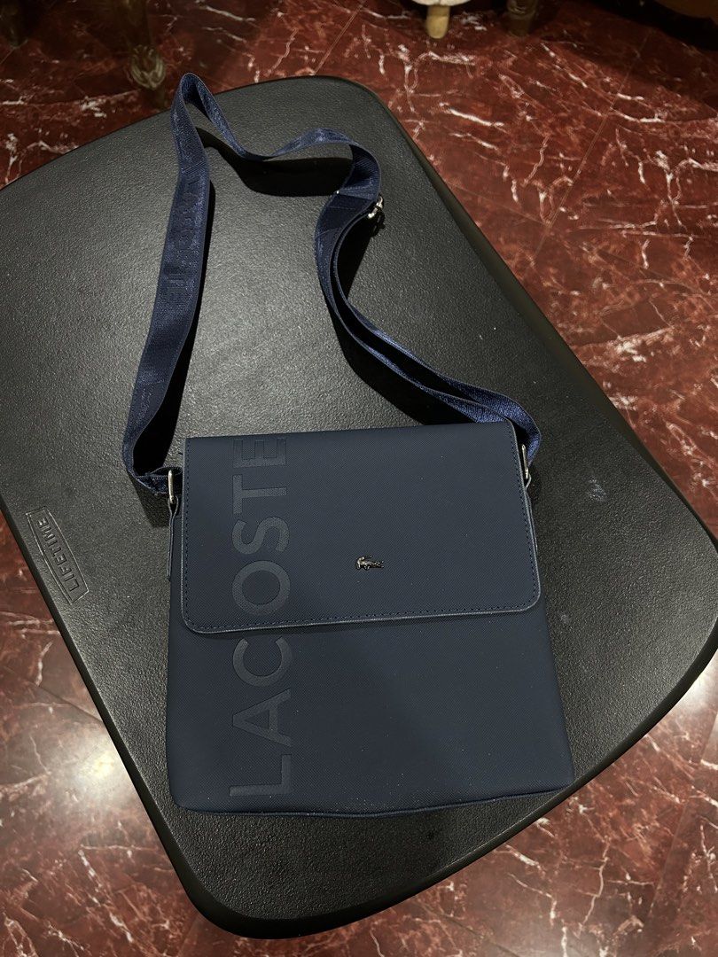 Lacoste Navy Blue Crossbody Bag (Category: Cross-body Bags) located in Manila. Submitted by drilskie0954204 (Listing ID 1460514993, Image 1). Description: - Navy blue Lacoste crossbody bag - Large embossed Lacoste logo on the front - Small Lacoste crocodile logo above the flap - Adjustable strap with Lacoste branding - Zipper pocket on the back - Ideal size for daily essentials.