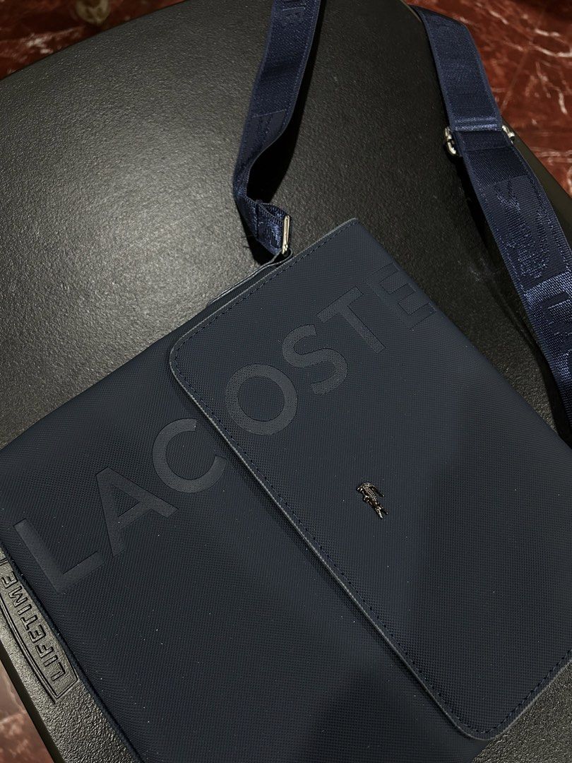 Lacoste Navy Blue Crossbody Bag (Category: Cross-body Bags) located in Manila. Submitted by drilskie0954204 (Listing ID 1460514993, Image 2). Description: - Navy blue Lacoste crossbody bag - Large embossed Lacoste logo on the front - Small Lacoste crocodile logo above the flap - Adjustable strap with Lacoste branding - Zipper pocket on the back - Ideal size for daily essentials.