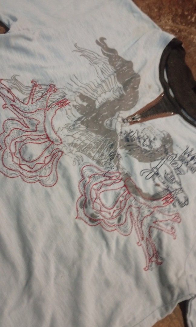 Light Blue Graphic T-Shirt with Eagle and Crown Design (Category: Tshirts & Polo Shirts ) located in Ubay. Submitted by pitipiww (Listing ID 1460528501, Image 2). Description: - Light blue t-shirt with a unique graphic print - Features a striking eagle with spread wings and a crown - Contrasting dark grey neckline - Made from soft and comfortable fabric - Ideal for casual everyday wear.