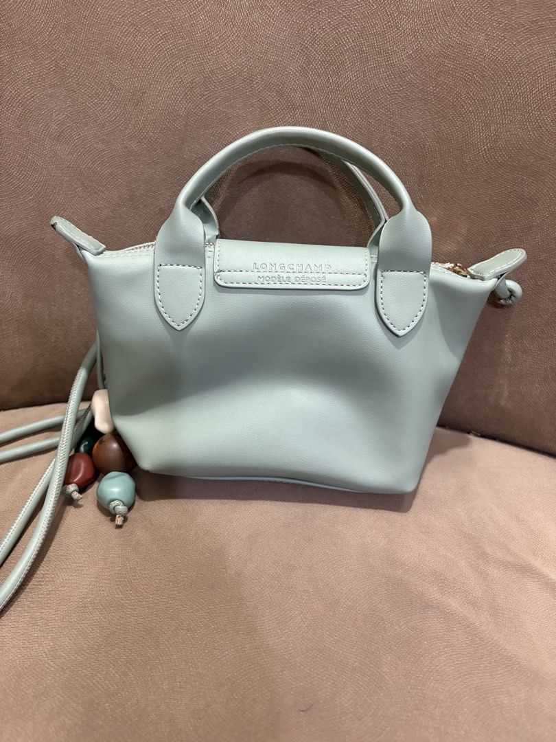 Longchamp Le Pliage Cuir Mini Top Handle Bag (Category: Luxury Bags & Wallets) located in Muntinlupa City. Submitted by xiannahailey (Listing ID 1460579215, Image 2). Description: - Light blue Longchamp mini top handle bag - Genuine leather material - Detachable shoulder strap included - Main zippered compartment with interior pockets - Adorable beaded charms - Versatile for everyday or special events.