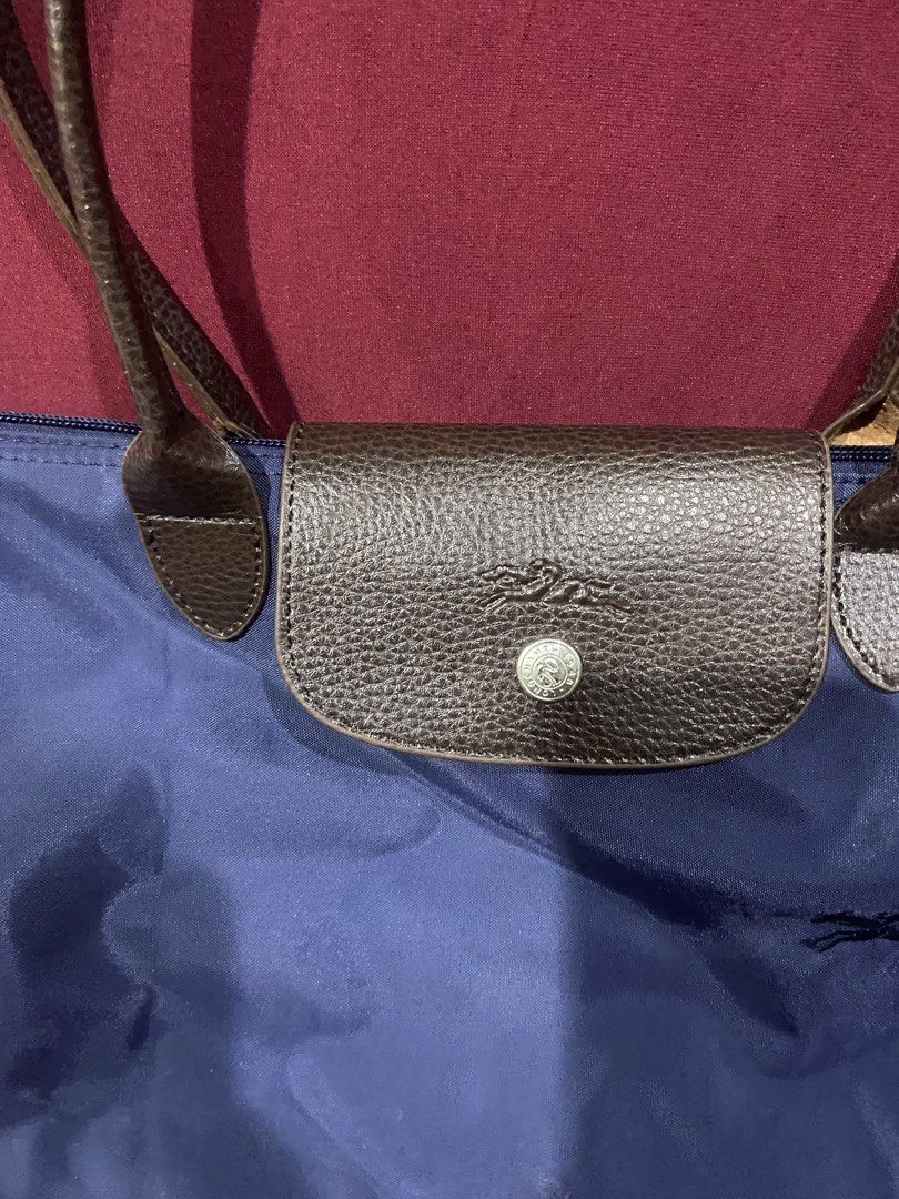 Longchamp Le Pliage Tote Bag Navy Blue (Category: Luxury Bags & Wallets) located in San Mateo. Submitted by japandeclutter (Listing ID 1460638041, Image 2). Description: - Classic Longchamp tote bag - Color: Navy blue nylon with brown leather handles and trim - Closure: Zip with snap-button flap - Features: Iconic embroidered horse logo on front - Ideal for: Everyday use, travel, carry-on.