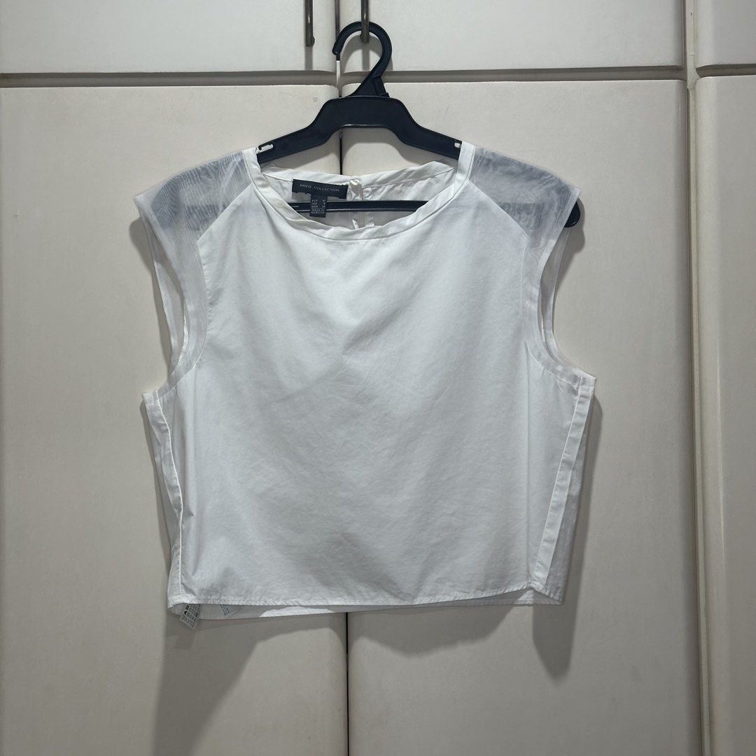 Mango - White Sleeveless Cropped Blouse (Category: Sleeveless) located in Muntinlupa City. Submitted by pickjes (Listing ID 1460700395, Image 1). Description: Brand: Mango (MNG Collection) Size: Medium Color: White Measurements: • Width - 18” • Length - 17.5” Condition: Used only once. No flaws. RFS: Decluttering Details: sleeveless, cropped white blouse from the Mango Collection featuring unique, semi-sheer mesh shoulder panels and a boat neckli