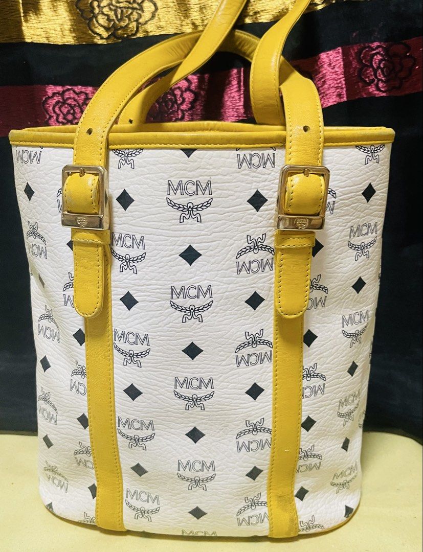 MCM Tote Bag White Yellow Monogram (Category: Luxury Bags & Wallets) located in Manila. Submitted by ermenchita71969 (Listing ID 1460664401, Image 2). Description: - Authentic MCM tote bag in white - Classic MCM monogram pattern all over - Stylish yellow leather trim and handles - Elegant gold-tone hardware with MCM logo plate - Spacious main compartment for all your essentials - Interior zippered pocket for secure storage - Ideal for everyday us