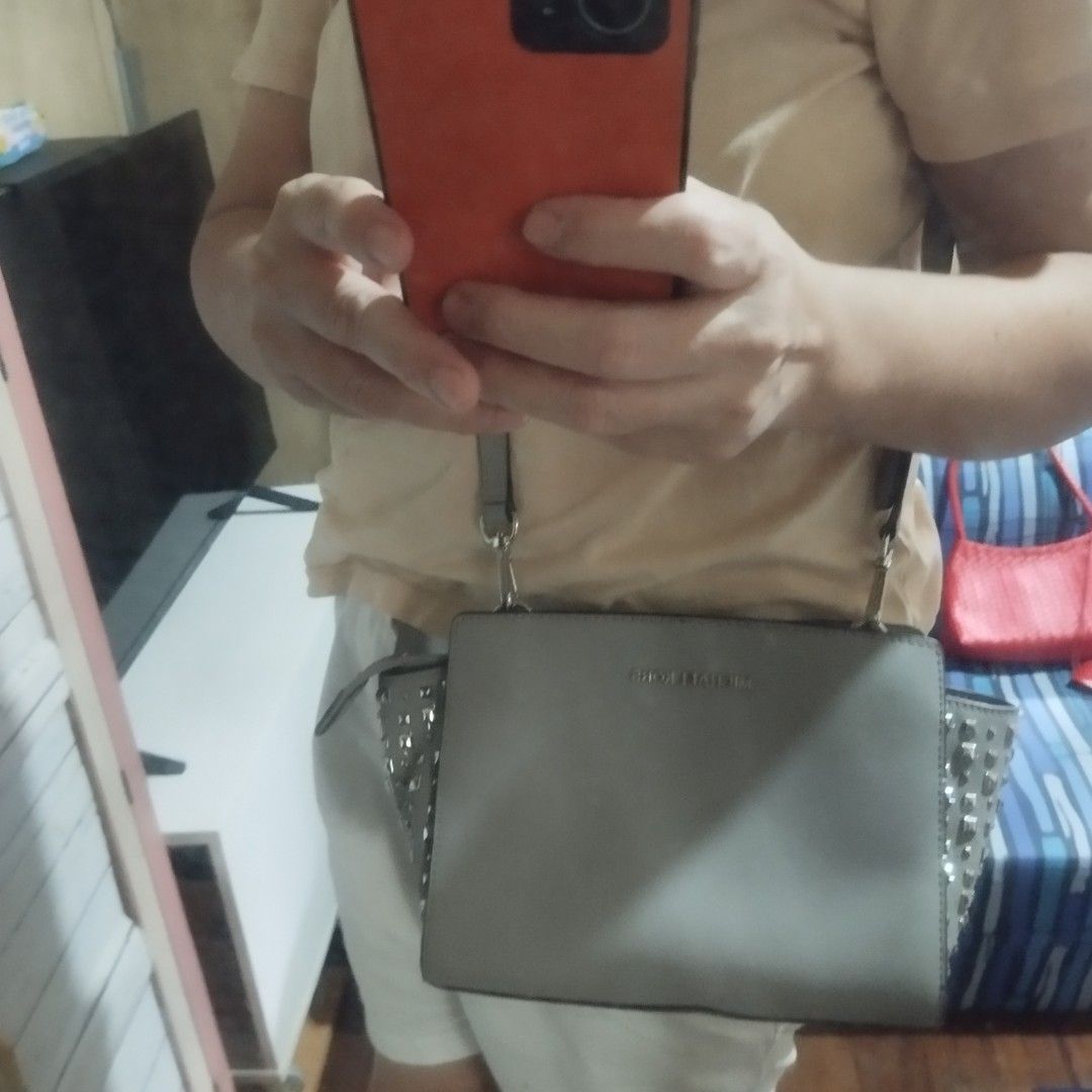 Michael Kors Grey Studded Crossbody Bag (Category: Cross-body Bags) located in Manila. Submitted by lene48 (Listing ID 1460567076, Image 3). Description: - Authentic Grey Michael Kors Crossbody Bag - Stylish silver stud details on the sides - Adjustable strap for comfortable wear - Secure zipper closure - Ideal for everyday use - Interior and exterior are clean - Comes with original dust bag, flaw last pic. .