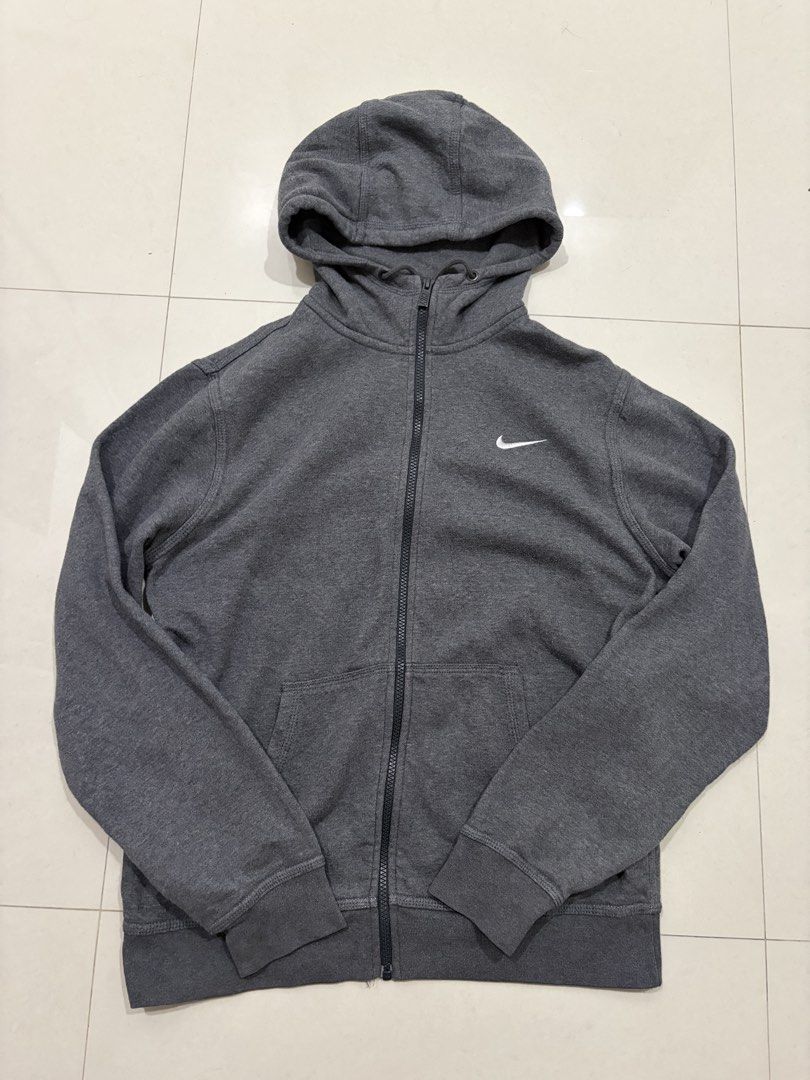 Nike Grey Zip-Up Hoodie (Category: Coats, Jackets and Outerwear) located in Marilao. Submitted by astroman.22 (Listing ID 1460543316, Image 1). Description: - Grey Nike zip-up hoodie - Classic Nike swoosh logo on chest - Two front pockets - Drawstring hood - Comfortable and versatile for everyday wear - Ideal for casual outings or workouts.
