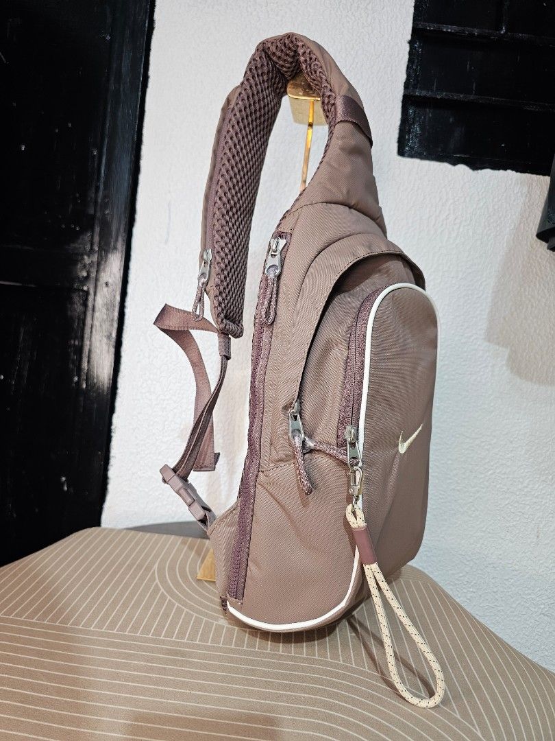Nike Sportswear Essentials Sling Bag (Category: Luxury Bags & Wallets) located in Baguio. Submitted by kayeonlineshop (Listing ID 1460568282, Image 2). Description: Taupe-colored Nike Sportswear Essentials Sling Bag with a golden Swoosh logo and a small cord zipper pull. Measurements L-40cm W-26cm.