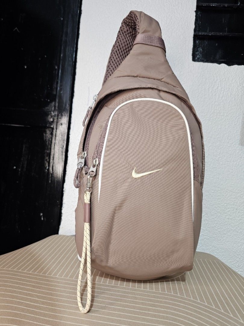 Nike Sportswear Essentials Sling Bag (Category: Luxury Bags & Wallets) located in Baguio. Submitted by kayeonlineshop (Listing ID 1460568282, Image 1). Description: Taupe-colored Nike Sportswear Essentials Sling Bag with a golden Swoosh logo and a small cord zipper pull. Measurements L-40cm W-26cm.