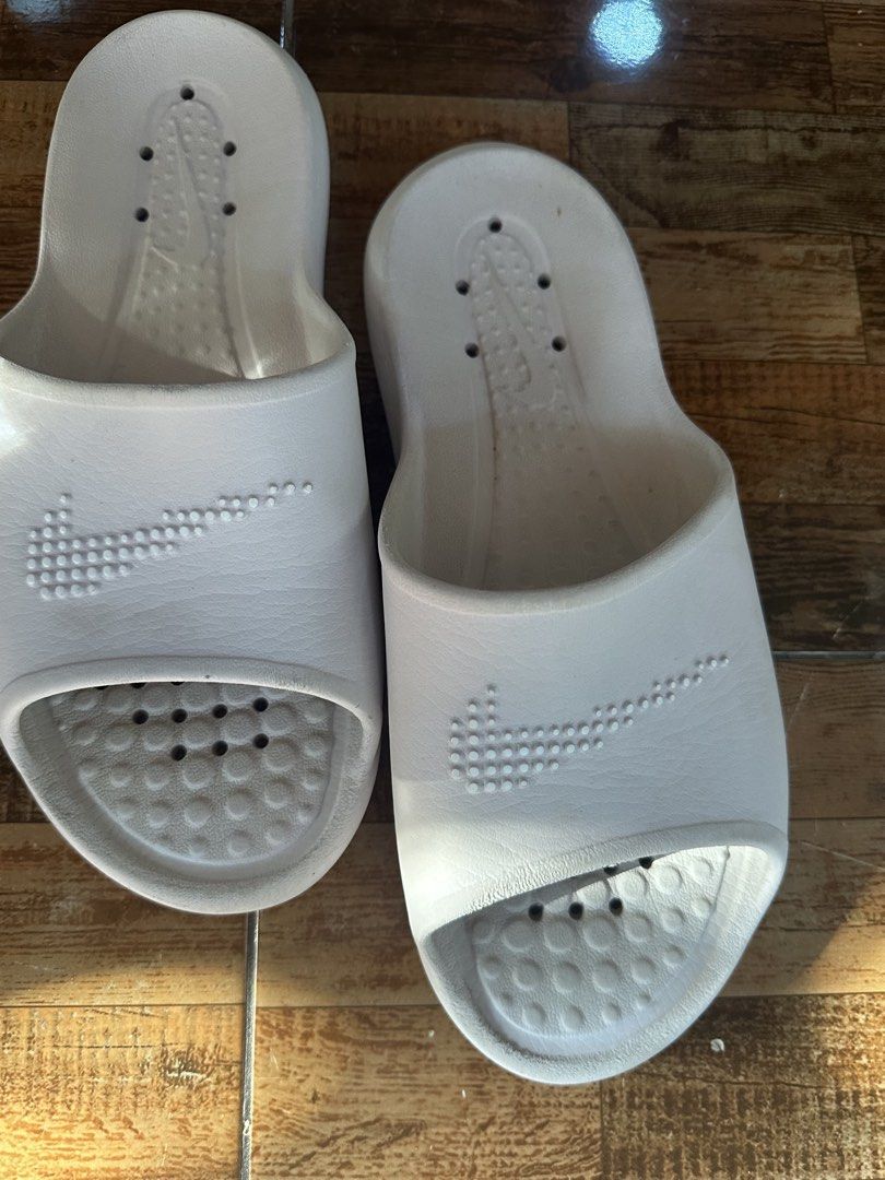 Nike White Slides (Category: Slippers & Slides) located in Digos. Submitted by venusacaro13427 (Listing ID 1460563758, Image 3). Description: - Classic white Nike slides - Features iconic Nike swoosh - Drainage holes on soles, ideal for shower or pool use - Shows minor scuffs from normal wear - Plenty of life left, great value - Easy slip-on style.