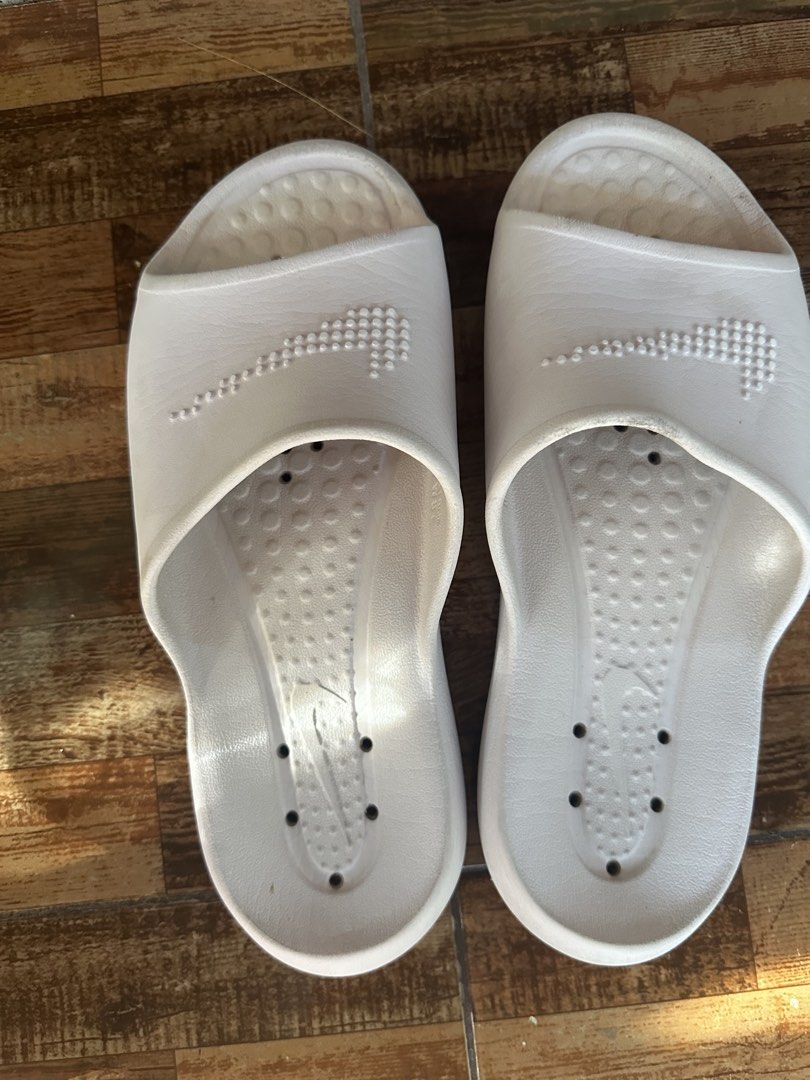 Nike White Slides (Category: Slippers & Slides) located in Digos. Submitted by venusacaro13427 (Listing ID 1460563758, Image 1). Description: - Classic white Nike slides - Features iconic Nike swoosh - Drainage holes on soles, ideal for shower or pool use - Shows minor scuffs from normal wear - Plenty of life left, great value - Easy slip-on style.