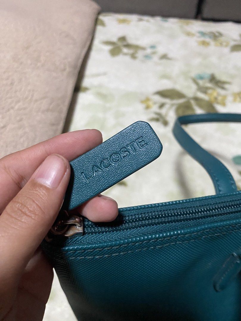 ORIGINAL Lacoste Teal Tote Bag (Category: Tote Bags) located in Tacurong. Submitted by phthriftclothing (Listing ID 1460626012, Image 3). Description: - Teal Lacoste tote bag - Made in Vietnam - Exterior: 100% PVC - Zipper closure for security - Iconic crocodile logo on the front - Small leather tag with 'LACOSTE' embossed - Interior lining is visible - Great size for daily use may dents lang sa ilalim pero hindi halata.