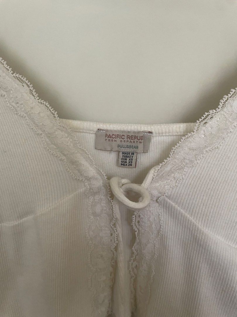 Pull & Bear White Lace Trim Ribbed Crop Top (Category: Sleeveless) located in Makati City. Submitted by alyslittlelamb (Listing ID 1460665038, Image 2). Description: - White ribbed crop top from Pull & Bear - Features delicate lace trim on neckline and hem - Tie front closure for a customizable fit - Adjustable spaghetti straps for comfort - Super cute and versatile piece, perfect for various outfits.