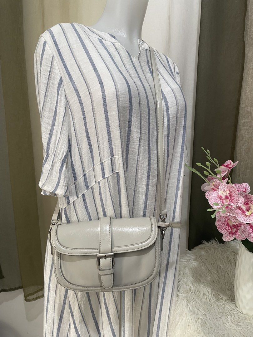 SQU’ARE Light Gray Crossbody Bag (Category: Shoulder Bags) located in Cabanatuan. Submitted by moraiahraven (Listing ID 1460581538, Image 1). Description: Cute and practical SQU’ARE crossbody / saddle bag in soft light gray (off-white). • Adjustable shoulder strap • Flap with buckle closure • Multiple interior compartments + zippered pocket • Black fabric lining • Silver-tone hardware Brand tag inside: SQU’ARE – “To draw inspiration from a square