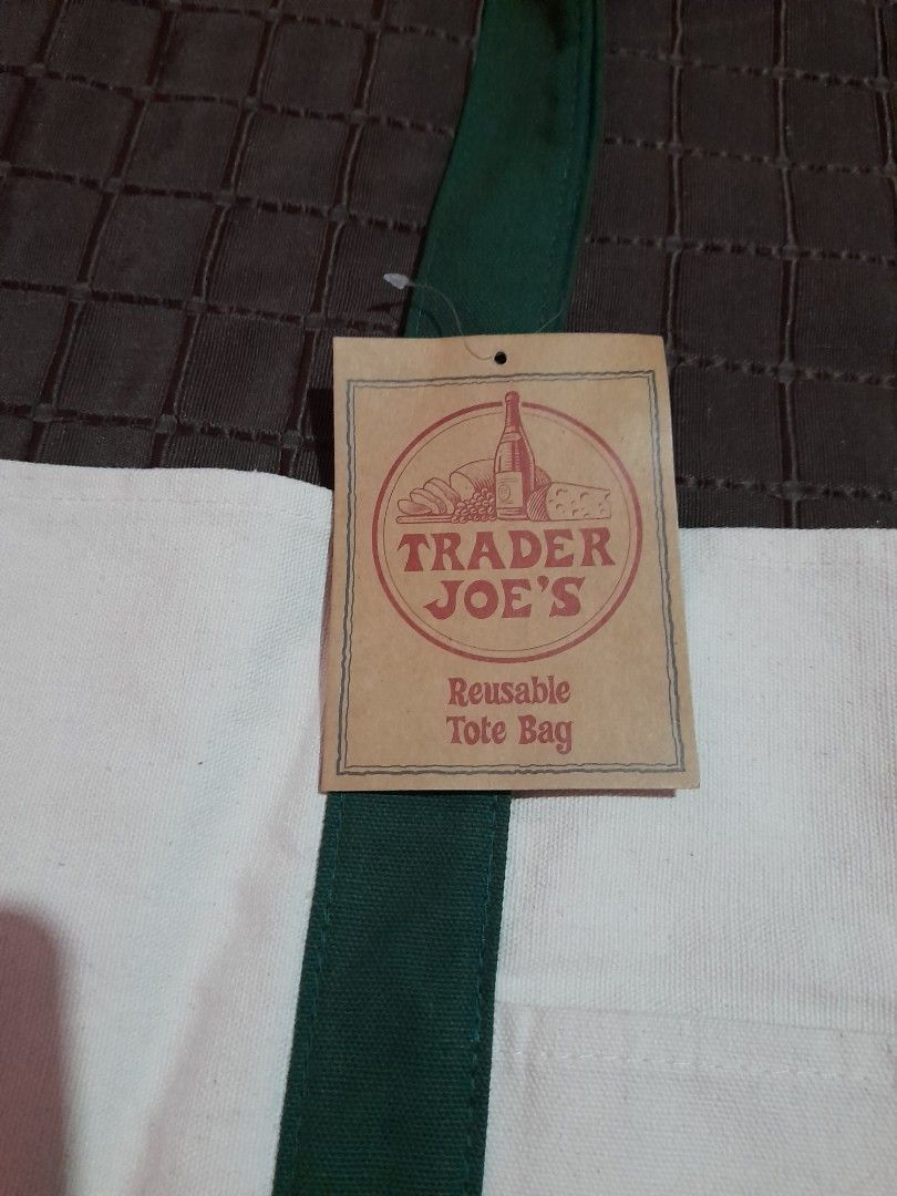 Trader Joe's Reusable Tote Bag (Category: Tote Bags) located in General Trias. Submitted by newberg0211 (Listing ID 1460656882, Image 3). Description: - Classic white and green Trader Joe's reusable tote bag - Material: 65% cotton, 35% polyester - Versatile use: groceries, beach trips, book bag - Care instructions: Machine wash cold, lay flat to dry - Note: May shrink slightly if machine dried - Imported from Vietnam.