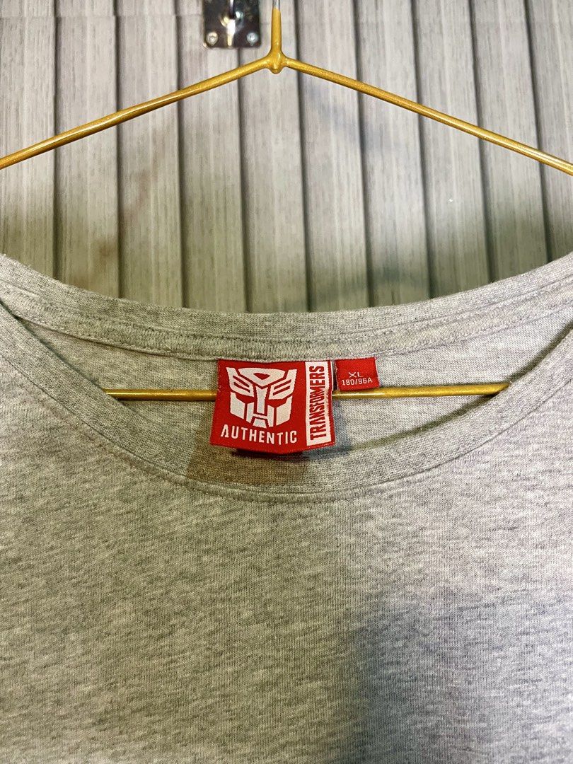 Transformers Authentic Grey T-Shirt XL (Category: Tshirts & Polo Shirts ) located in Manila. Submitted by fabufinds29 (Listing ID 1460561900, Image 3). Description: - Authentic Grey Transformers T-shirt - Size: XL - Features the iconic Autobot logo on the chest pocket - 'TRANSFORMERS' text printed on the back - Additional 'TRANSFORMERS' branding on a tag near the hem.