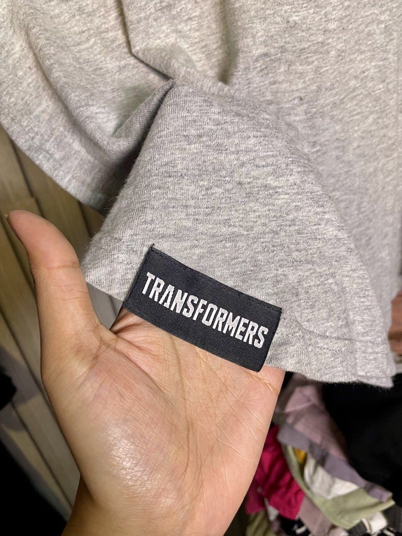 Transformers Authentic Grey T-Shirt XL (Category: Tshirts & Polo Shirts ) located in Manila. Submitted by fabufinds29 (Listing ID 1460561900, Image 2). Description: - Authentic Grey Transformers T-shirt - Size: XL - Features the iconic Autobot logo on the chest pocket - 'TRANSFORMERS' text printed on the back - Additional 'TRANSFORMERS' branding on a tag near the hem.
